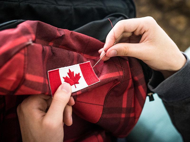 hand sewing Canada patch into shirt